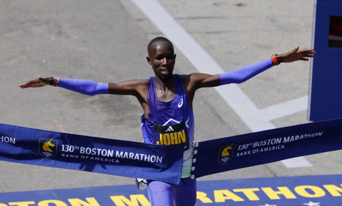 John Korir crossing Boston Marathon finish line with arms spread in celebration