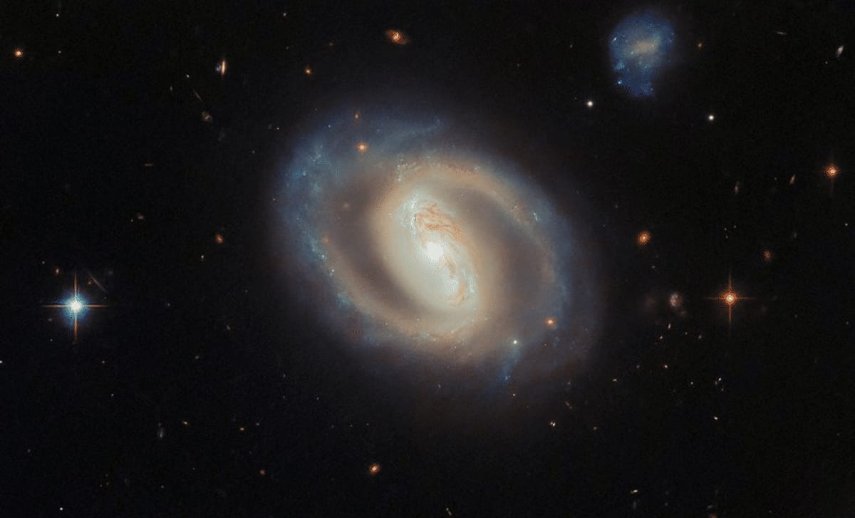 ** Spiral galaxy IC 486 captured by Hubble showing glowing center and blue star-forming regions