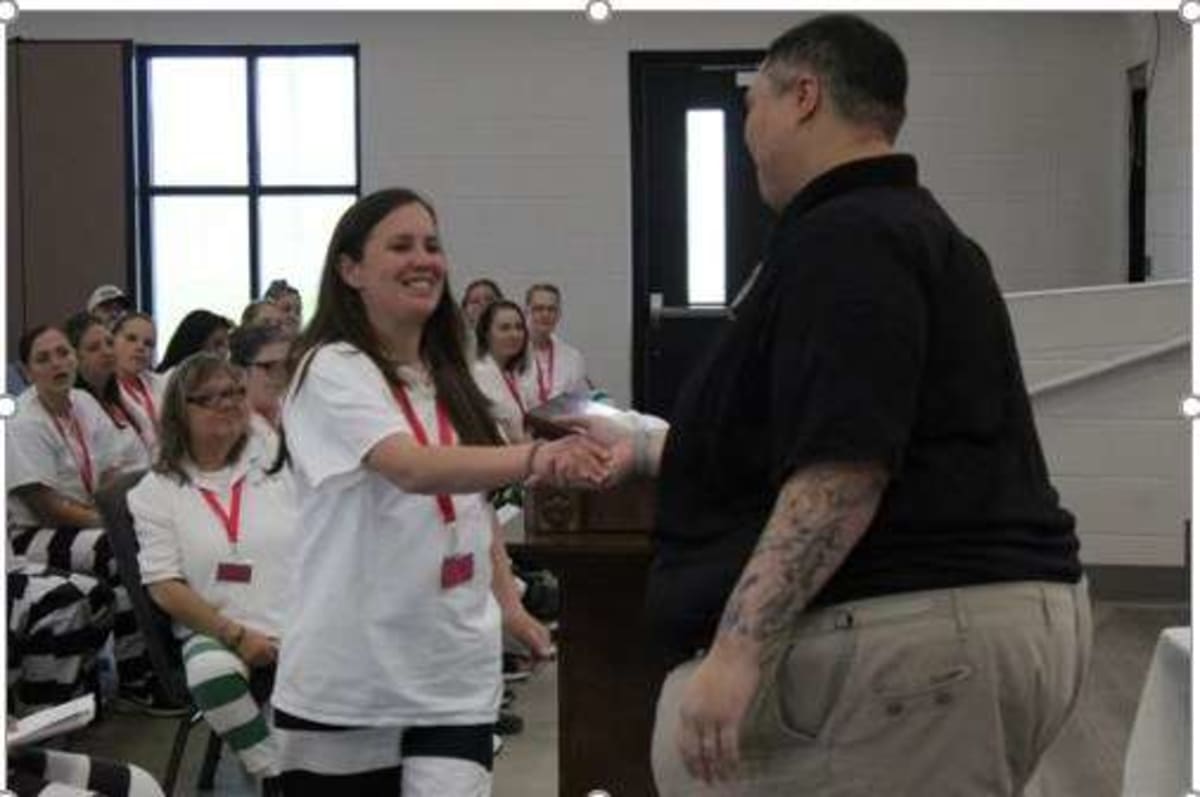 Women graduates standing together holding certificates at Mississippi prison recovery program ceremony
