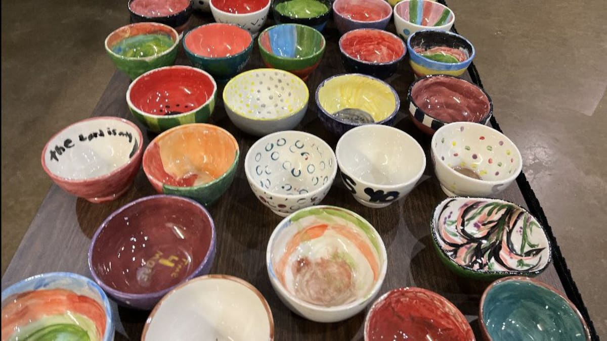 Colorful handmade ceramic bowls filled with soup at community fundraising event for hunger relief