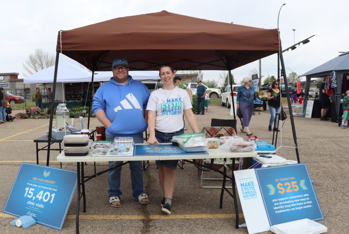 Young volunteers selling baked goods at outdoor farmers market table for cystic fibrosis fundraiser