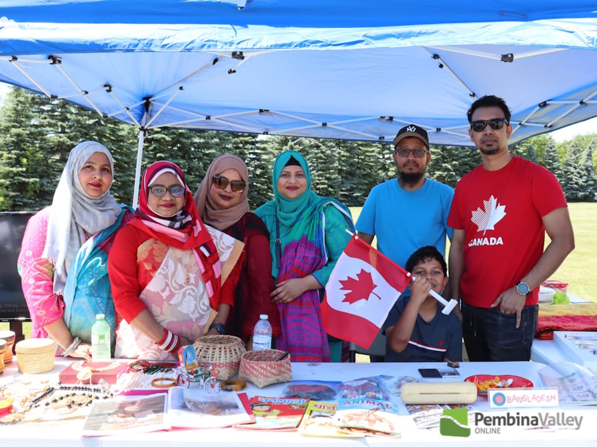 Diverse group of new Canadian citizens celebrating at outdoor festival with flags and cultural displays