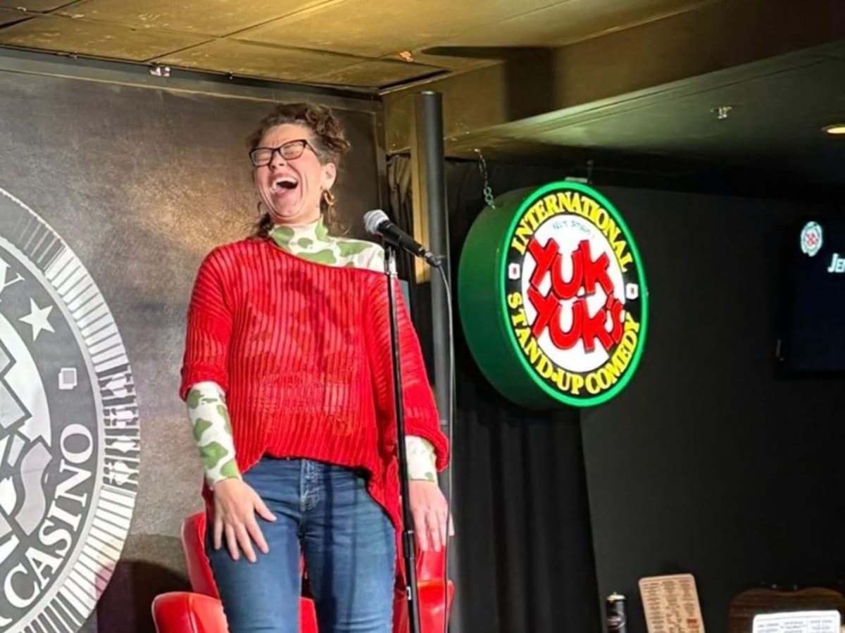 Breast cancer survivor Jennifer Gordon performing stand-up comedy on stage with microphone