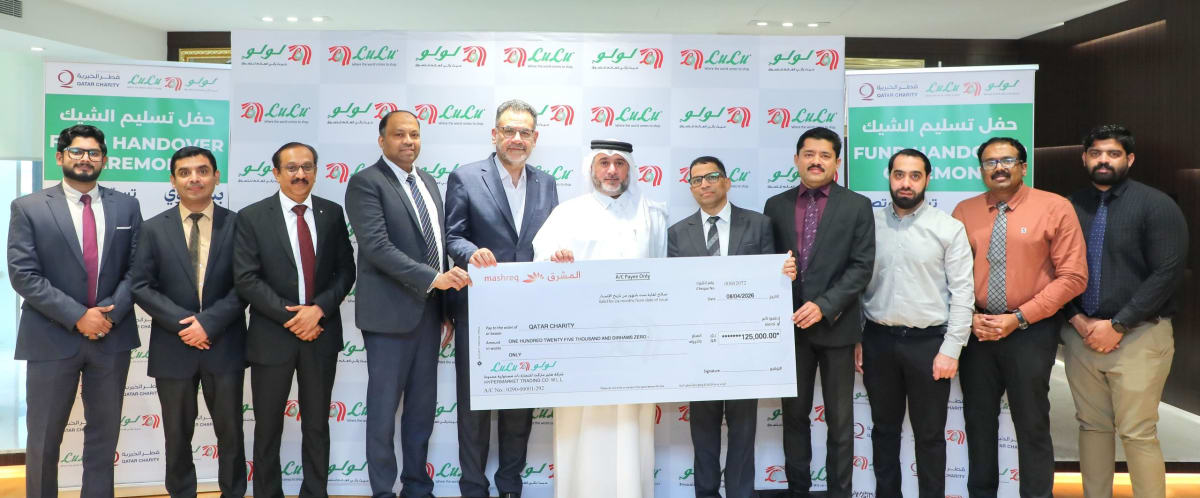 LuLu Hypermarket representative presenting oversized donation check to Qatar Charity official at ceremony