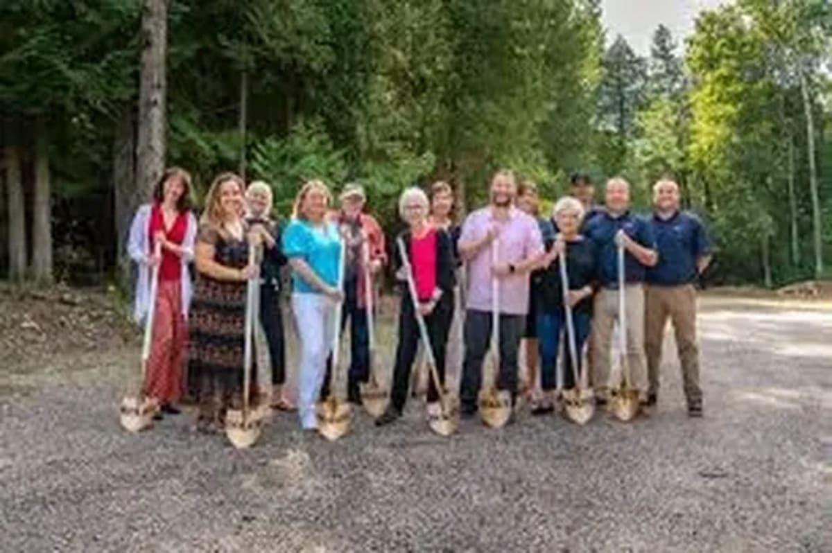 Volunteers with brooms and rakes preparing outdoor theater grounds for summer season