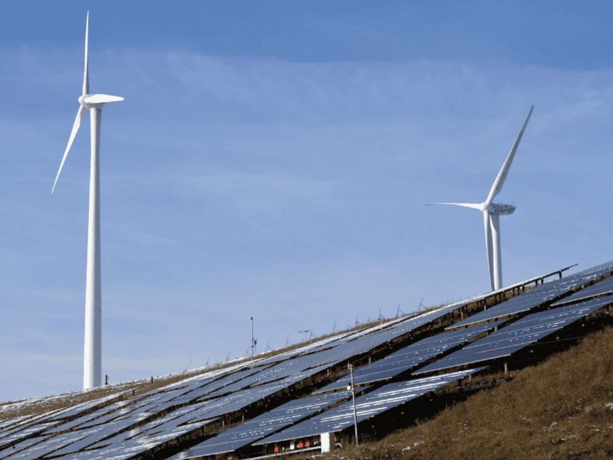 ** Solar panels and wind turbines generating clean renewable electricity in developing region