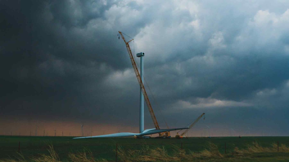 Wind turbines standing in Australian farmland with sheep grazing in green pasture below