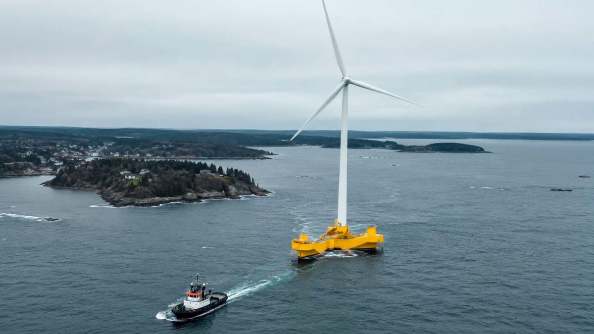 Large white wind turbine mounted on floating concrete platform in ocean waters off Maine coast