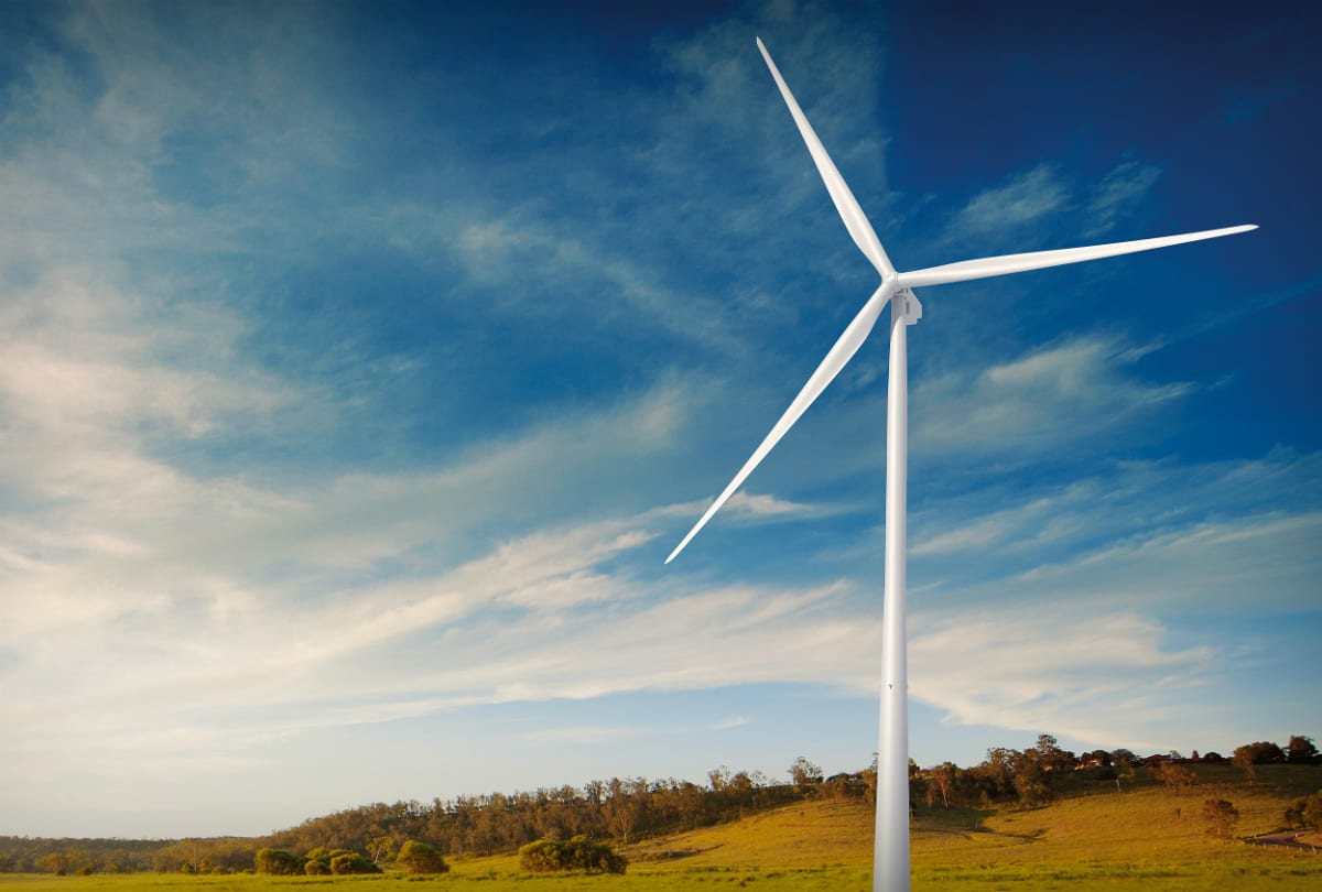Wind turbines spinning against blue Norwegian sky with mountains in background