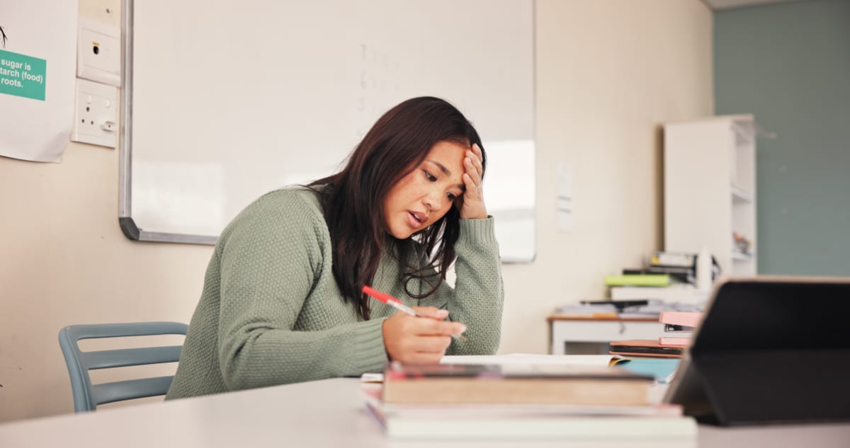 ** Teacher providing encouraging feedback to student reviewing graded assignment in bright classroom