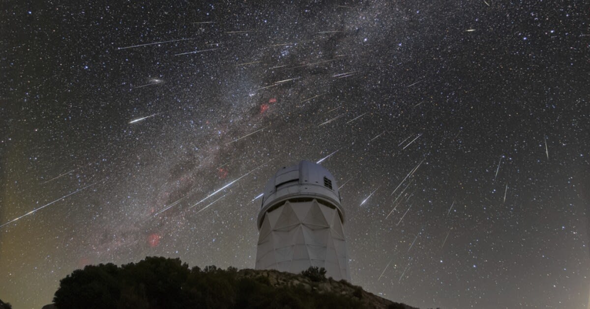 Meteor shower streaking across night sky above astronomical observatory telescope dome