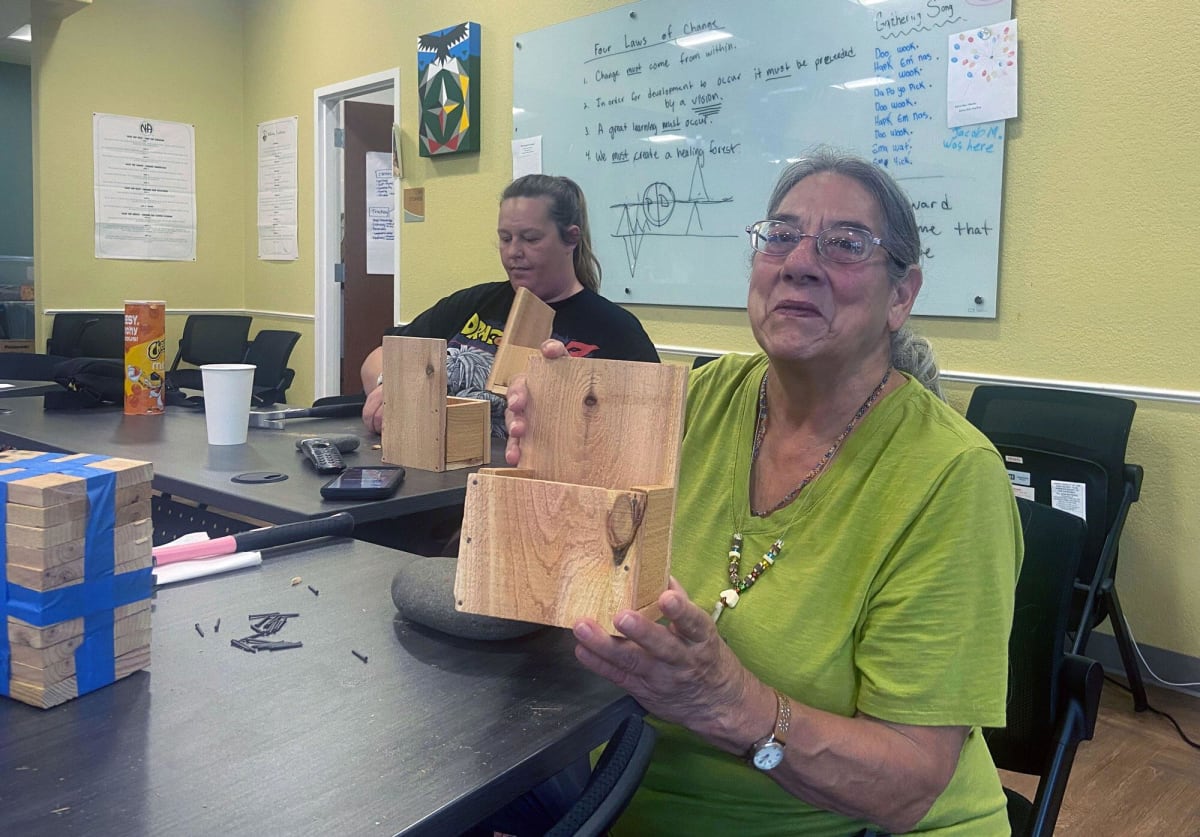 People assembling wooden planters together at table in community room during Tribal Roots recovery program