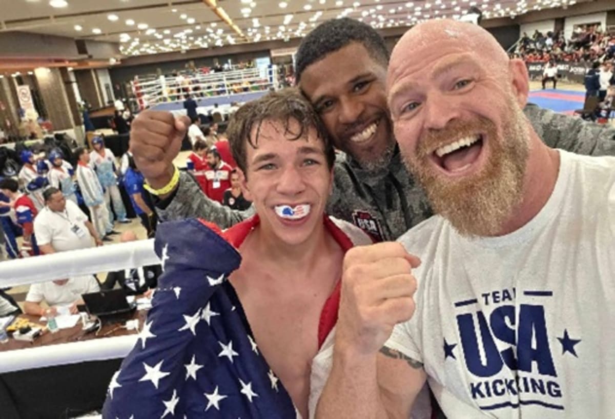 Young kickboxer Aidan Lambert holding gold medal wearing Team USA uniform