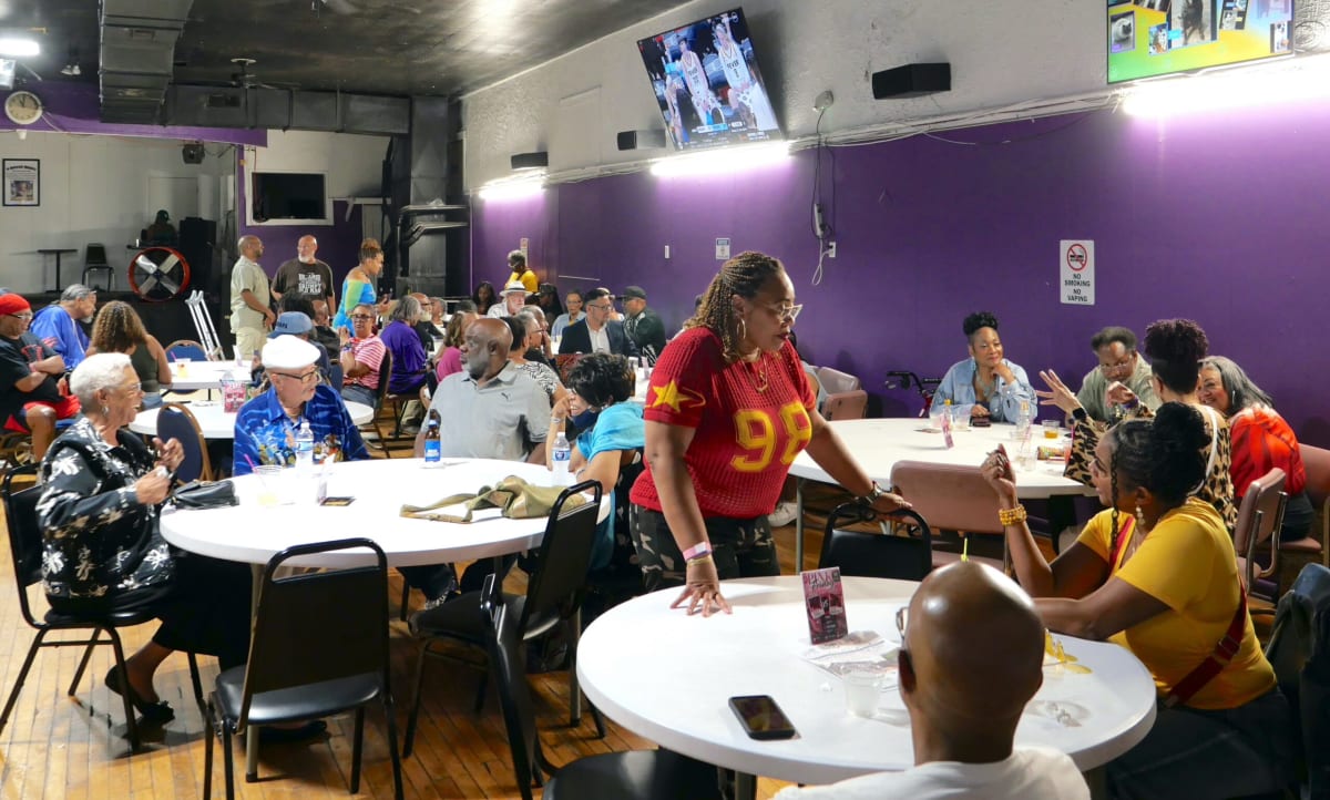 Large African American family gathering under canopies at sunny outdoor park reunion celebration