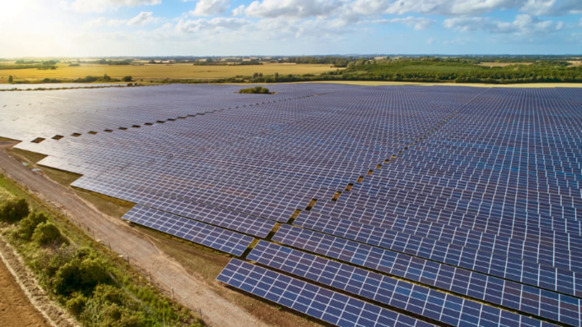 Solar panels and wind turbines against blue sky representing Massachusetts clean energy expansion