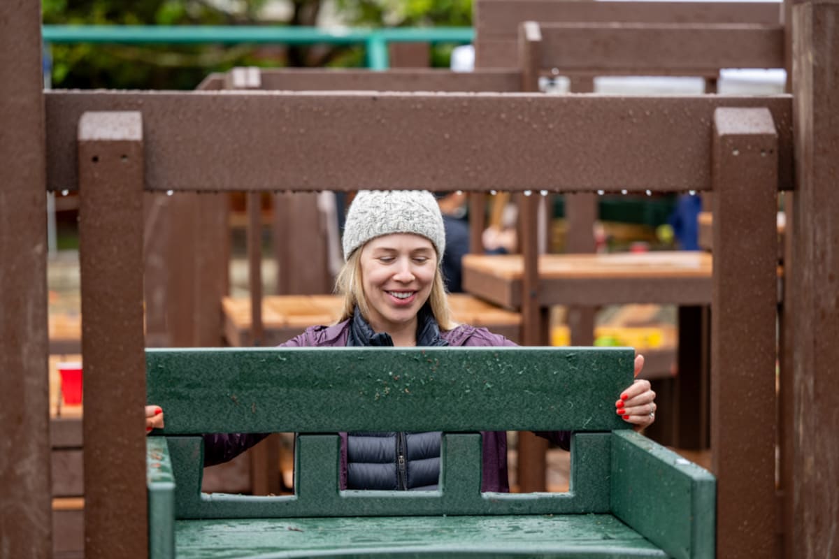 Volunteers working together in rain to build wooden castle-themed playground structure at Folsom park
