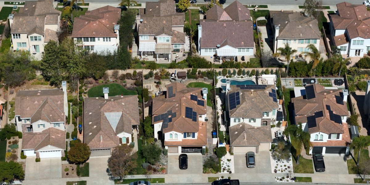Young couple holding house keys while standing with supportive parents outside new home