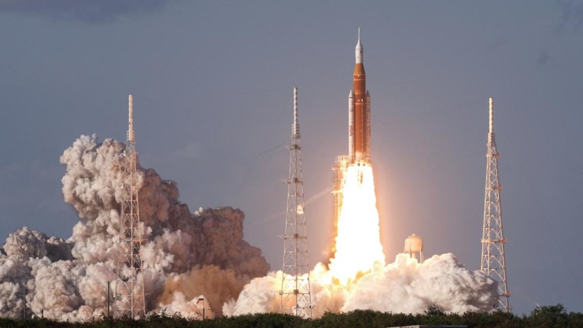 NASA's orange and white Artemis II rocket launching from Kennedy Space Center at dusk
