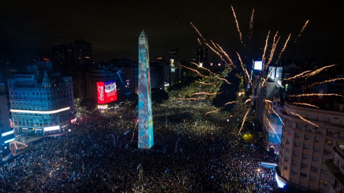 Argentine soccer fans celebrating in the streets waving blue and white flags near Buenos Aires Obelisk