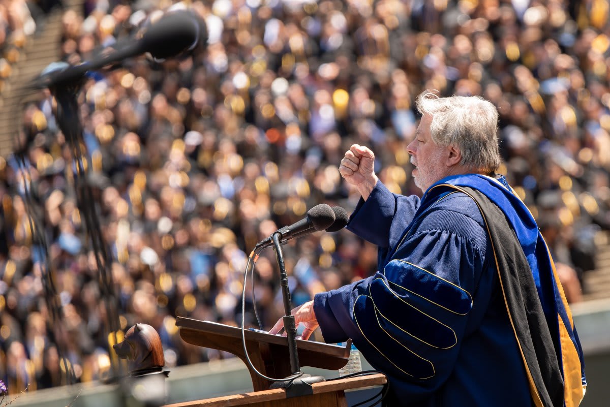 Steve Wozniak speaking at graduation ceremony with enthusiastic students in caps and gowns
