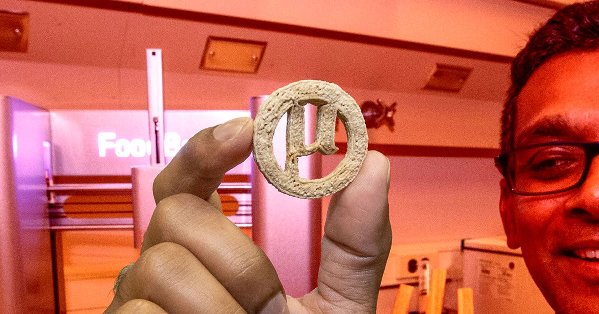Researcher holding 3D printed cookies shaped like Greek letter mu made from recycled plastic materials