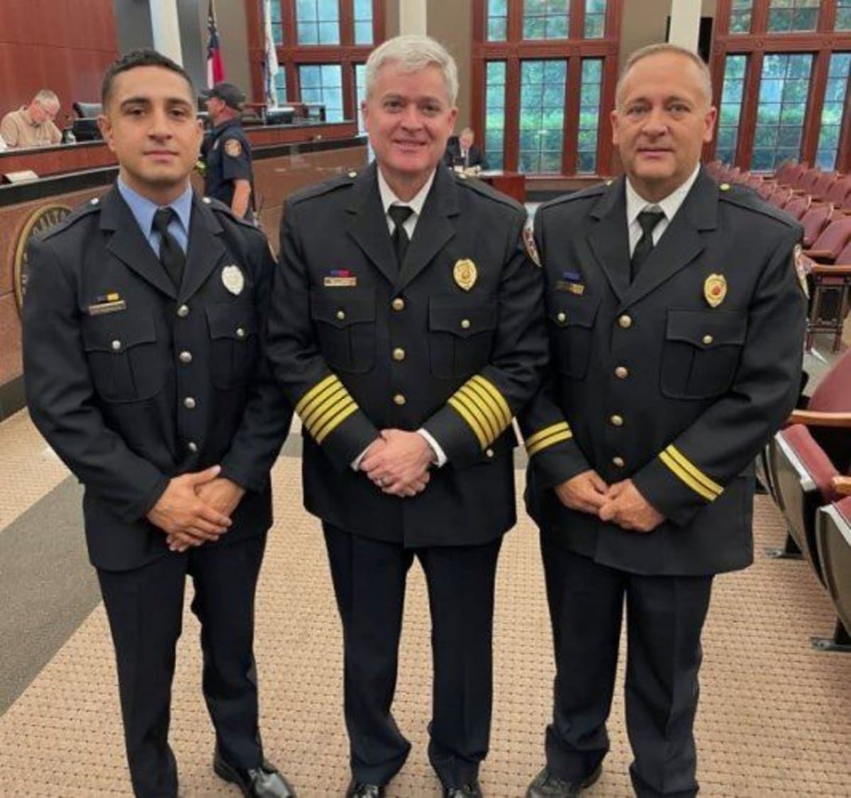 Fire Chief Matt Daniel presenting certificates to two firefighters in uniform at recognition ceremony