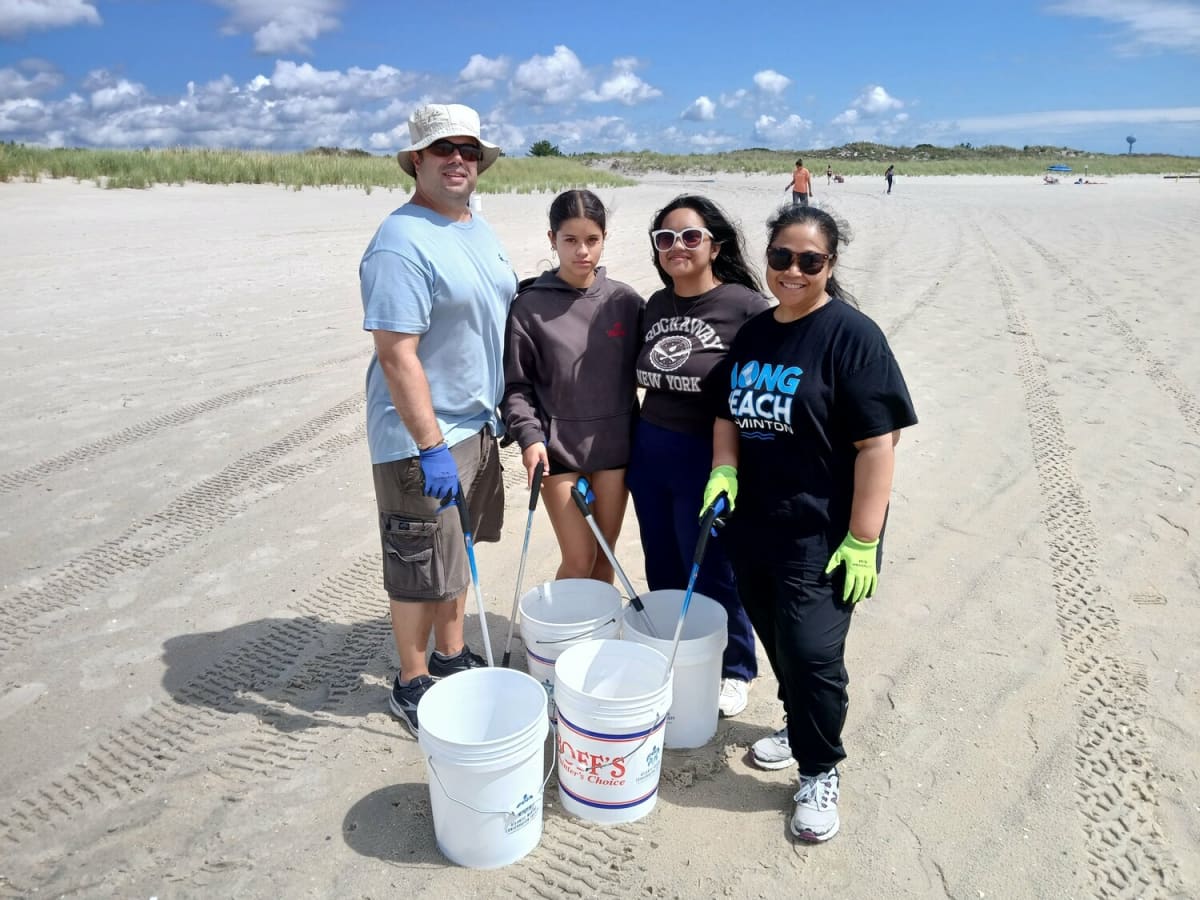 The Sisko family holding cleanup buckets on Lido Beach during community environmental volunteer event