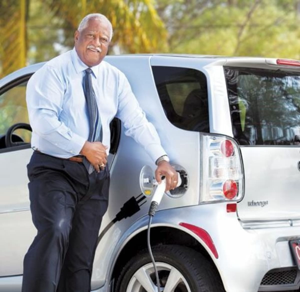 John C. Felder standing beside electric vehicles donated to students for automotive training