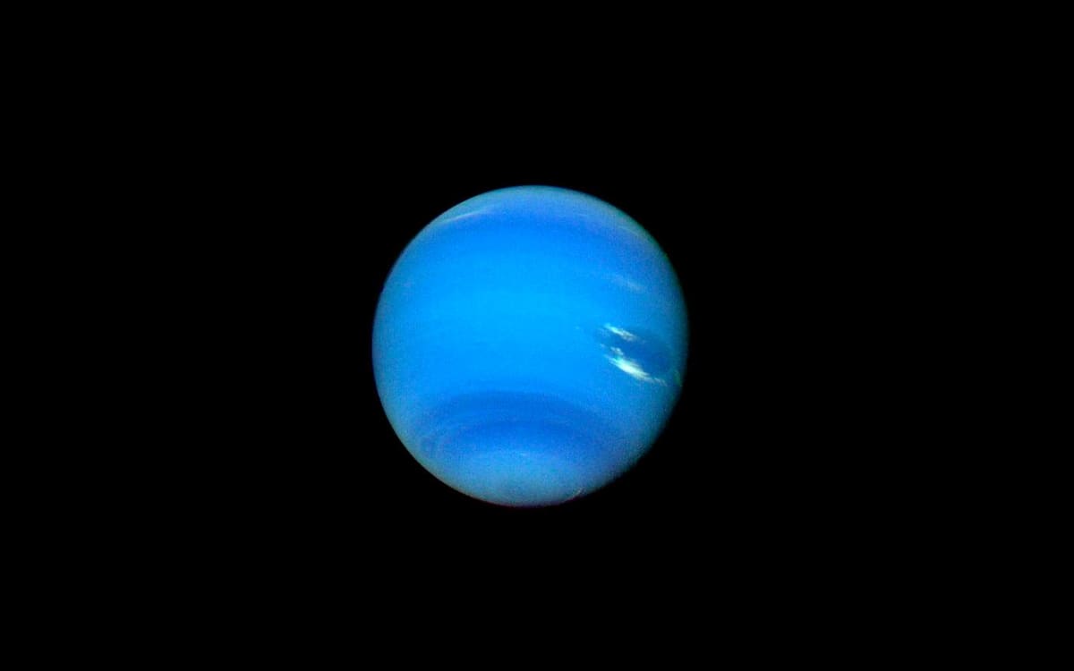 Artistic rendering of Neptune's moon Nereid orbiting in space with icy surface visible
