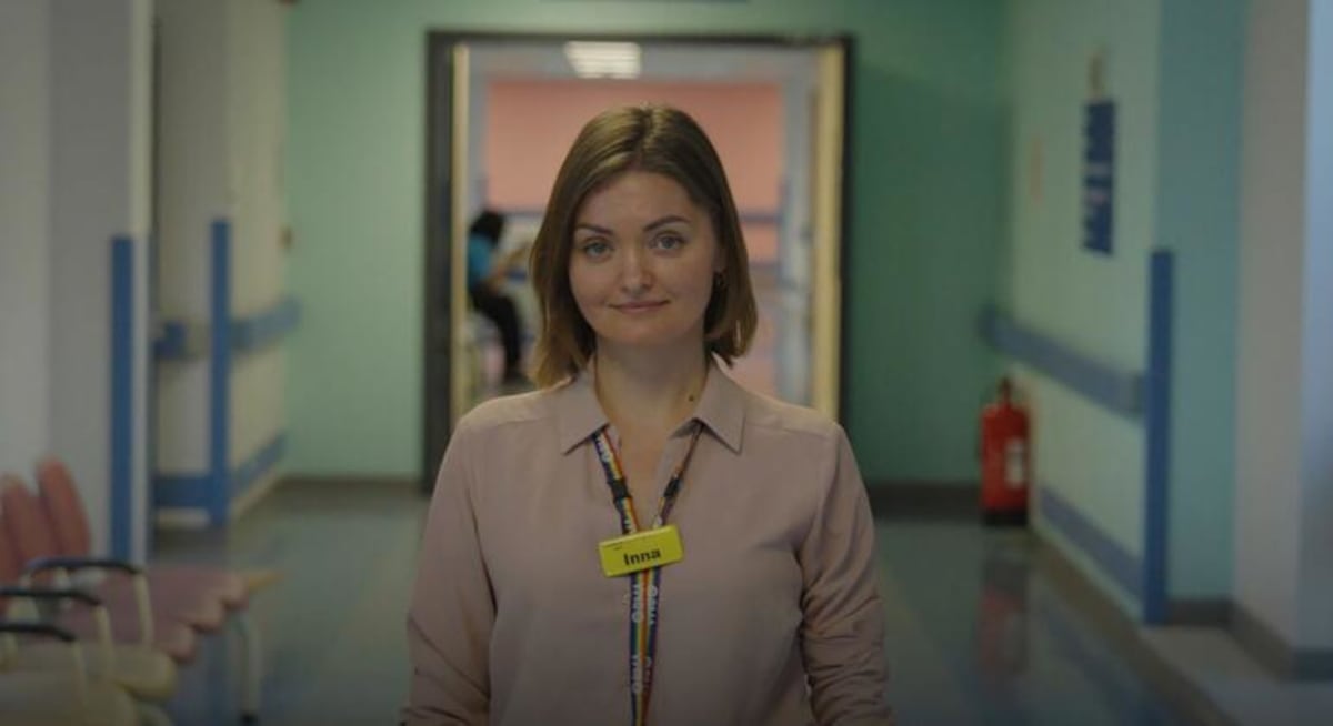** Dr. Inna Soldatenko in medical attire standing in Queen Elizabeth Hospital London corridor