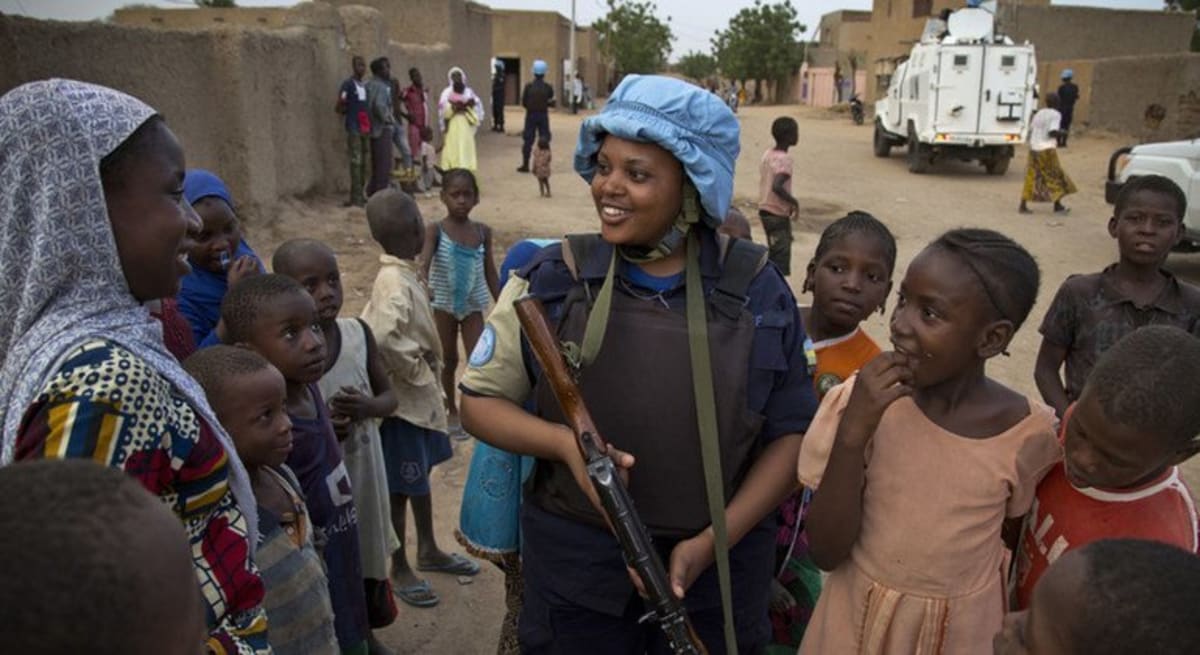 ** UN police officer in blue beret speaking with community members during peacekeeping patrol