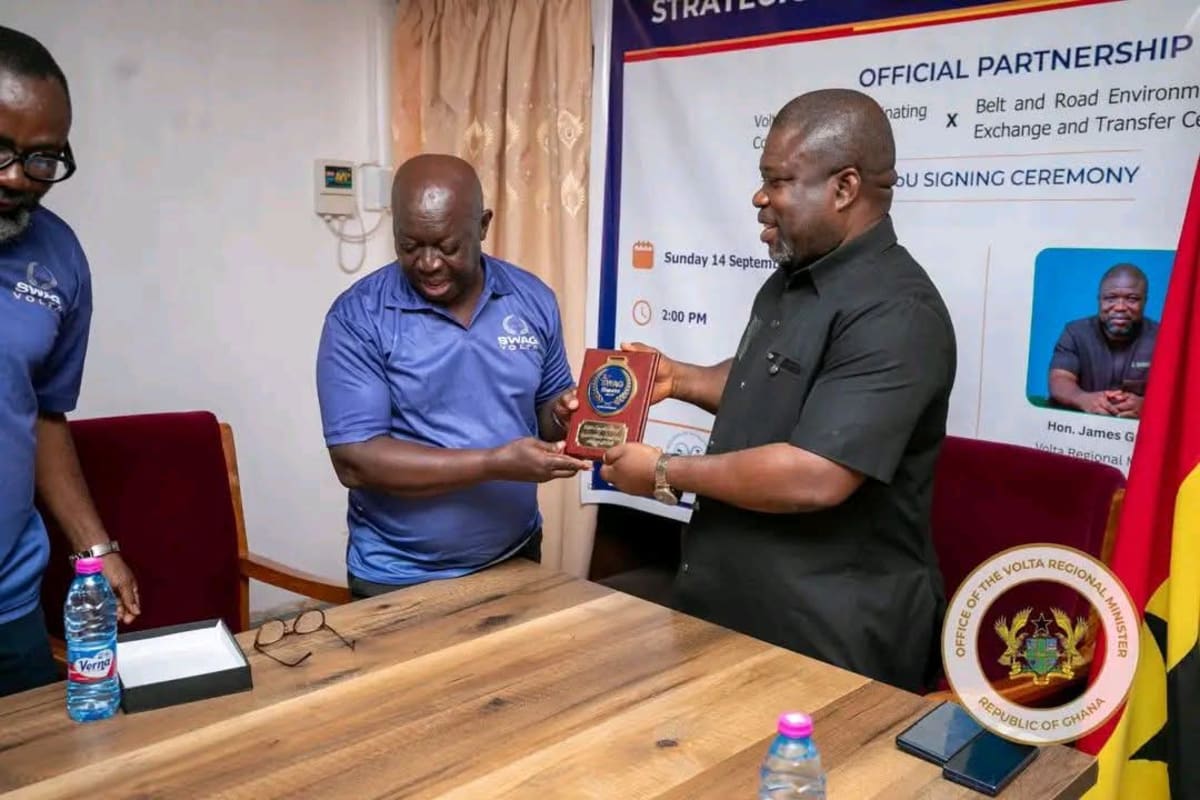 Young athletes training at sports facility in Ghana's Volta Region with stadium in background