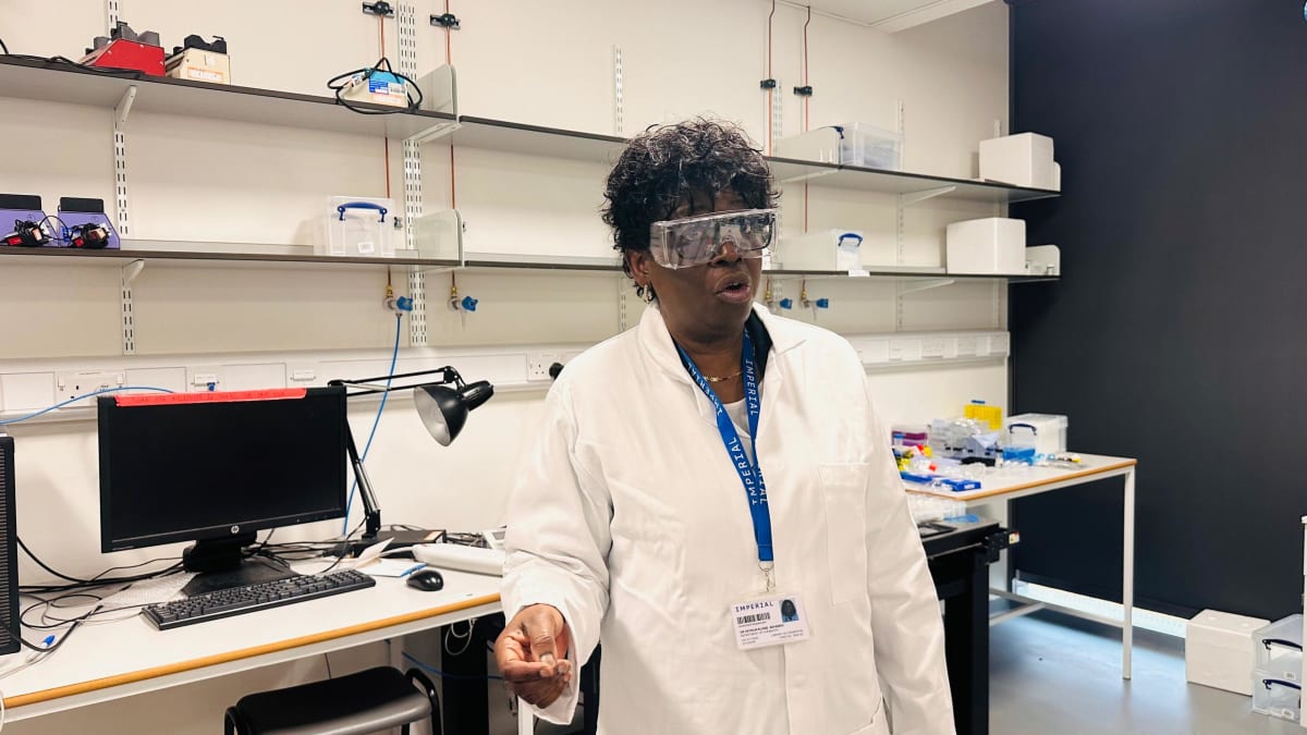 Dr. Ofosua Adi-Dako examining microscopic lab-on-a-chip device showing tiny fluid channels for drug testing