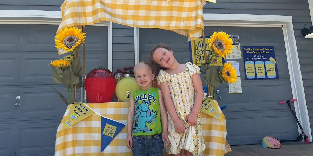 Four-year-old Emmett Bledsoe standing at his lemonade stand after completing cancer treatment