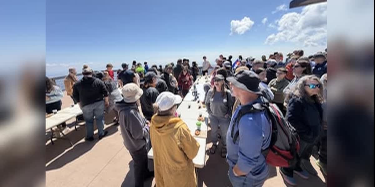 Large group of people holding coffee cups and doughnuts at Pikes Peak summit