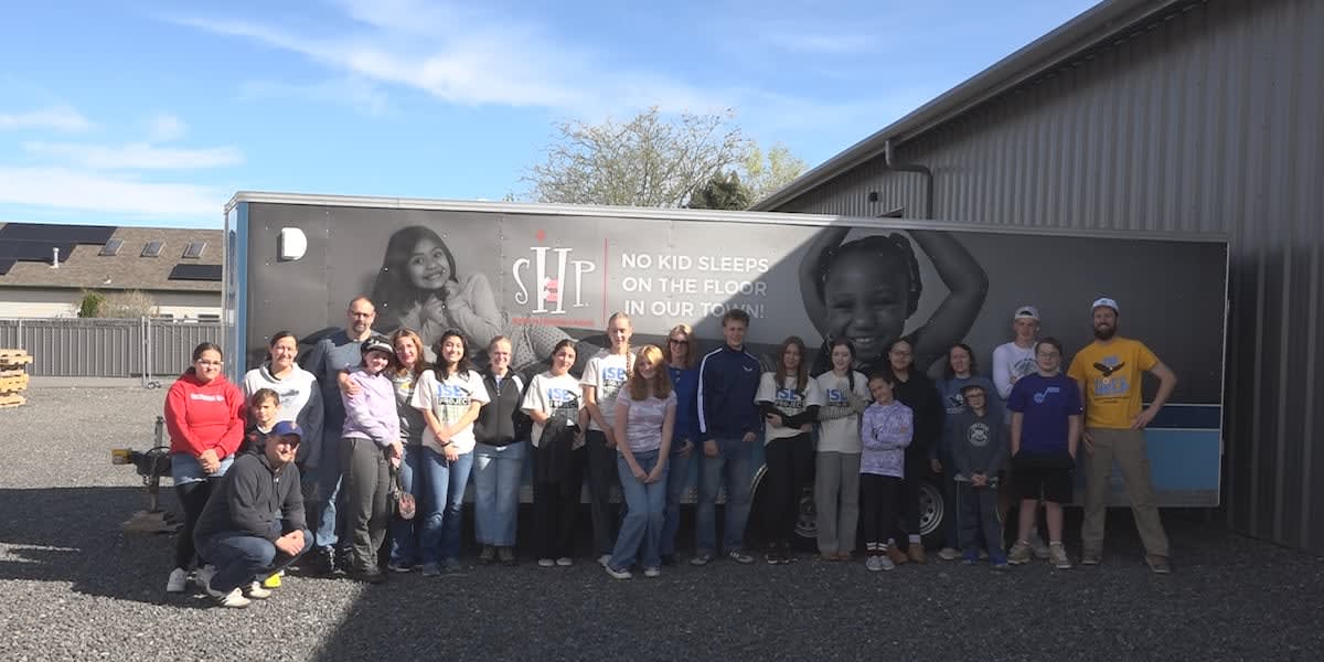 International exchange students using power tools to build wooden bed frames for children