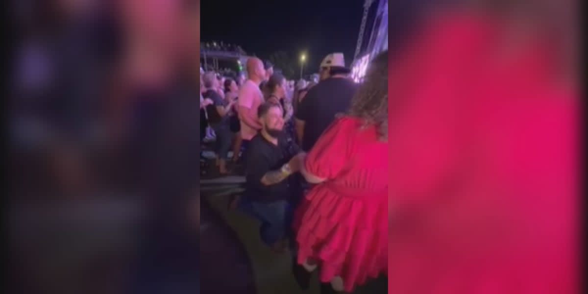Couple embracing at outdoor concert venue during Kane Brown performance proposal moment