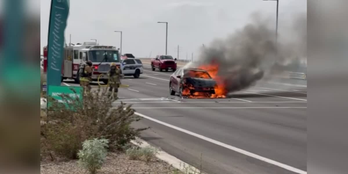 Firefighters extinguishing flames from a crashed vehicle at a Phoenix intersection after civilian rescue