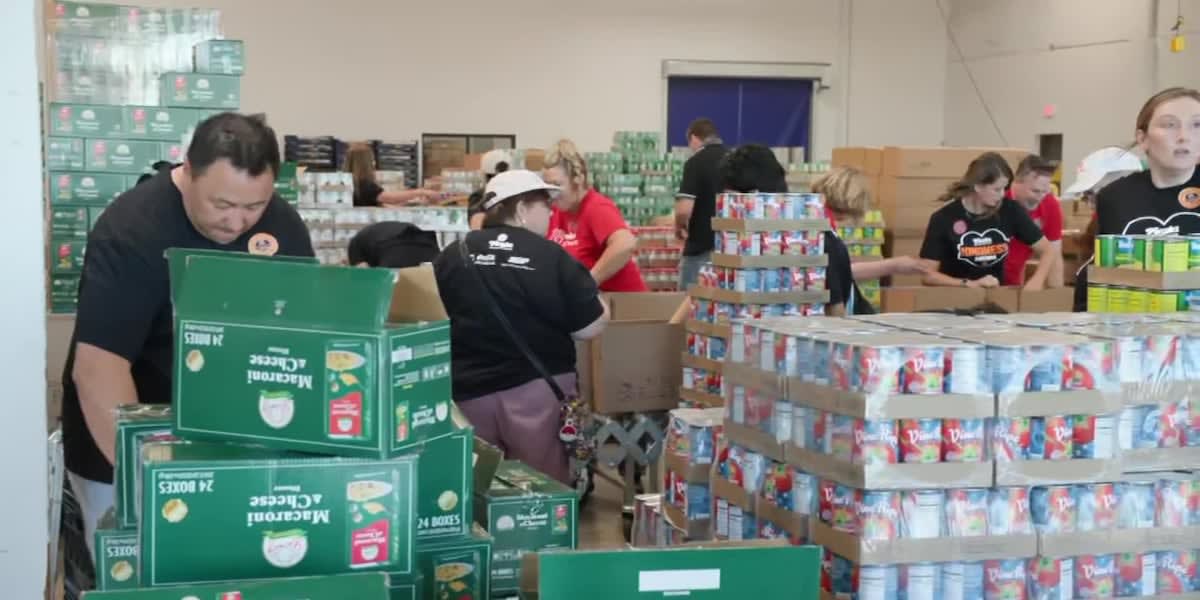 Large group of volunteers in warehouse packing meal boxes into pallets at St. Mary's Food Bank