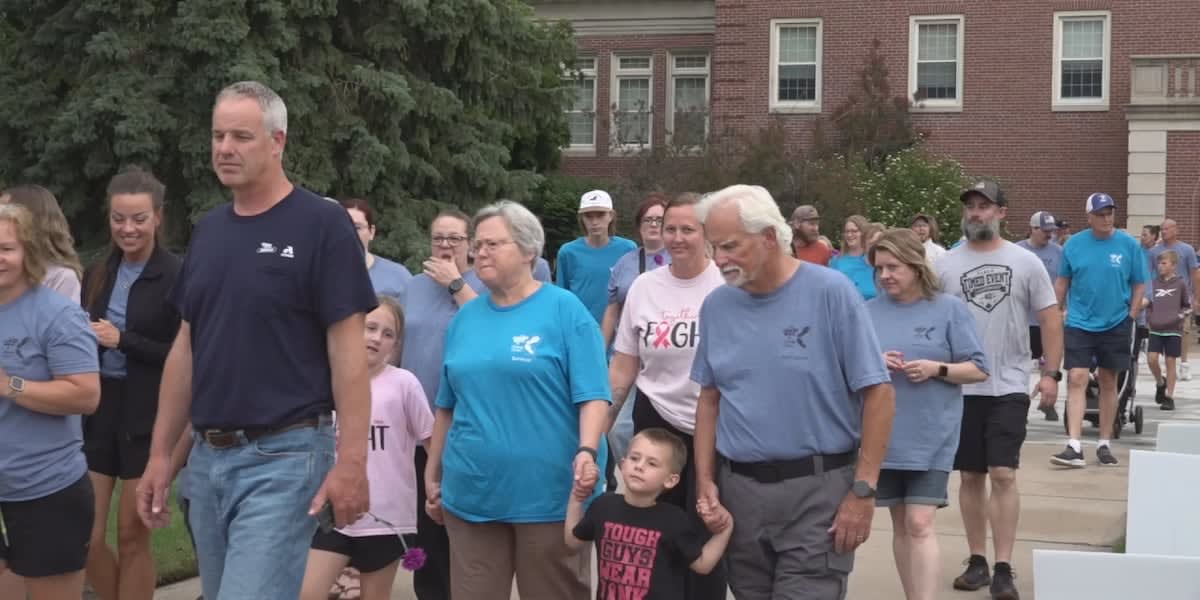 Cancer survivors and community members walking together at evening fundraising event on college campus