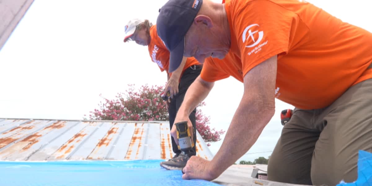 Volunteer securing blue tarp on damaged roof in Louisiana flood recovery effort