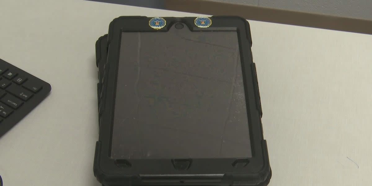 Police officer holding iPad while speaking with mental health clinician during crisis response