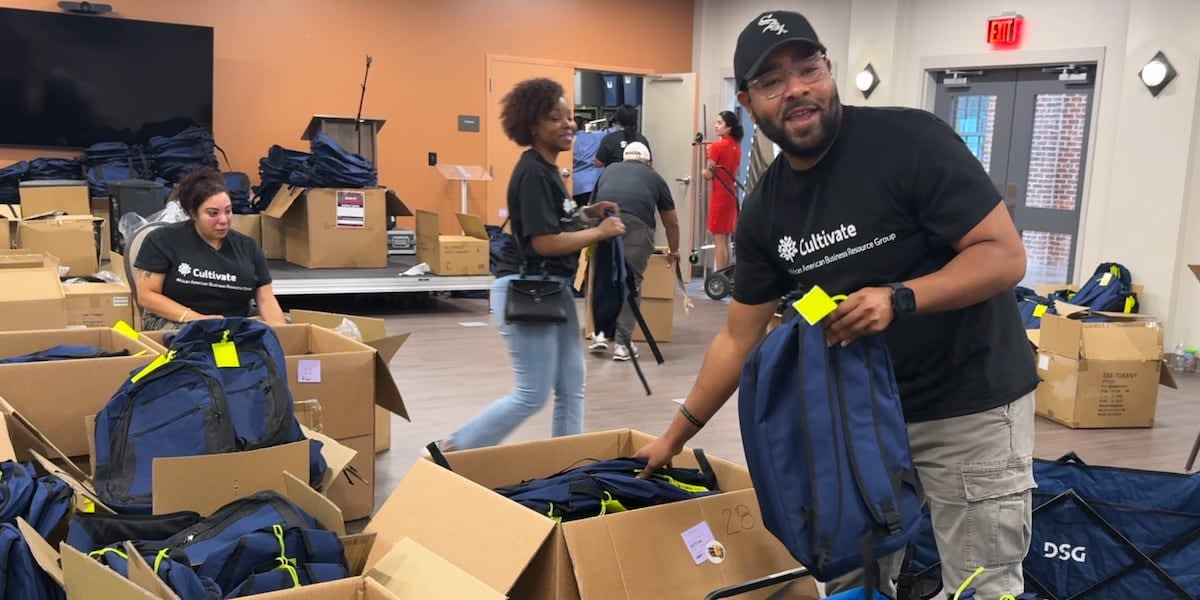 Children and families receiving free backpacks filled with school supplies at community celebration event