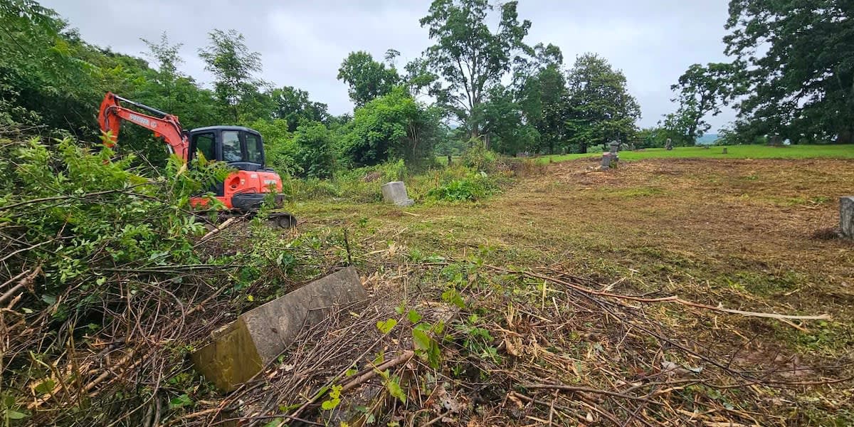Heavy equipment clearing overgrown brush from historic cemetery graves in Morristown, Tennessee