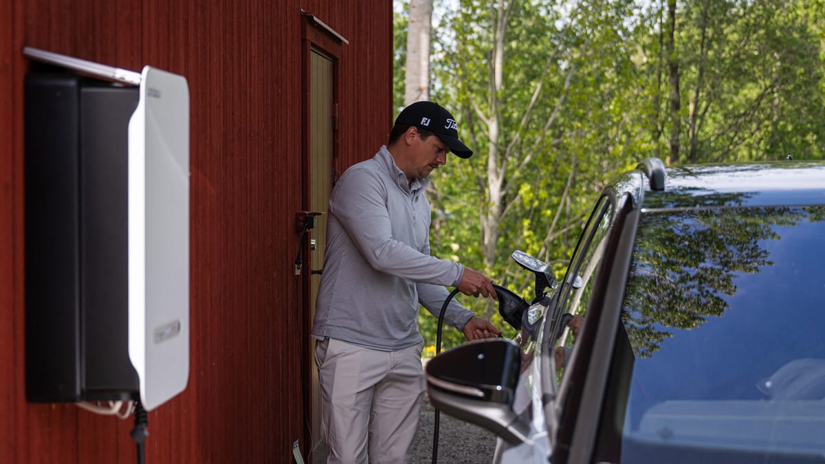 Electric vehicle plugged in at home garage, sending power back to electrical grid
