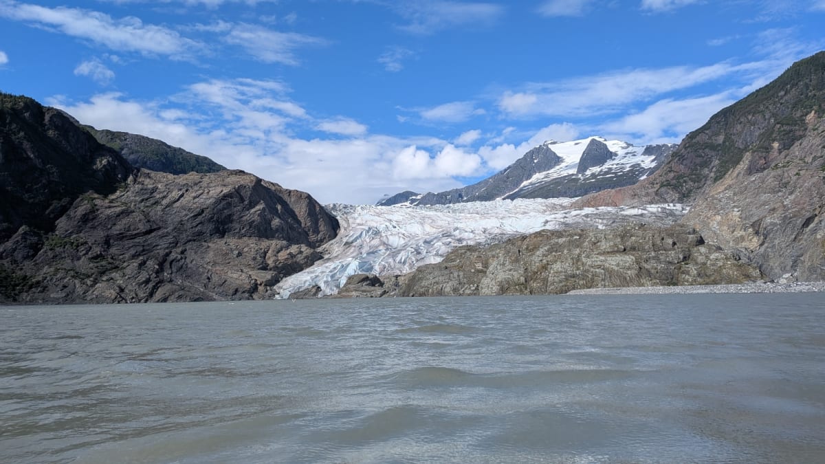 Mendenhall Glacier towers over residential Juneau neighborhood with protective flood barriers along river
