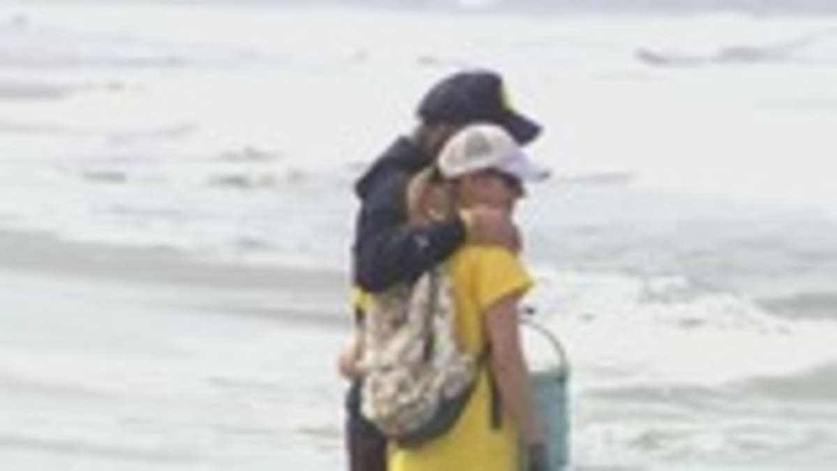 ** Volunteers with trash bags cleaning sandy Encinitas beach in memory of young girl