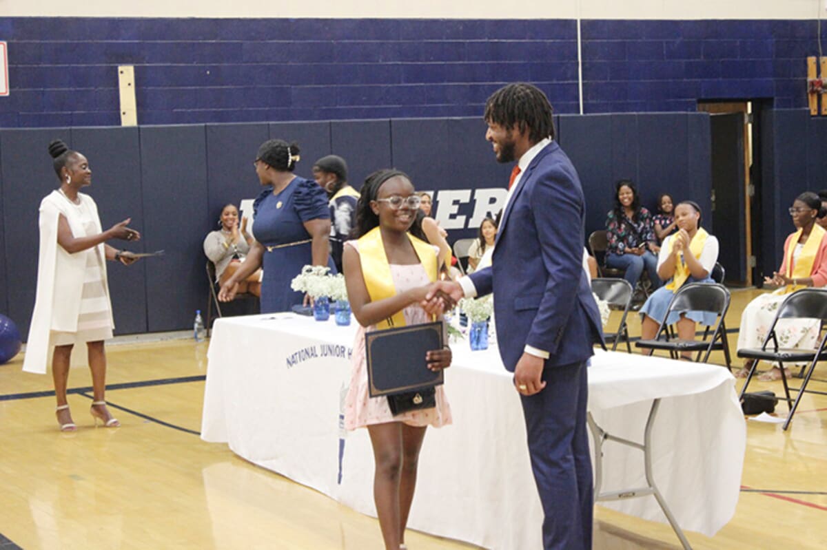 Middle school principal Barrington Atkins speaking to students at assembly with microphone in hand