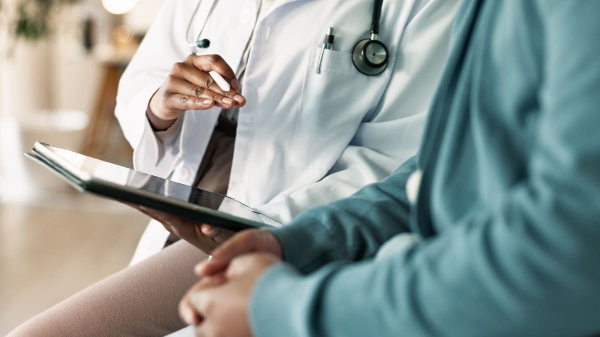 Doctor reviewing genetic test results on computer screen with young patient and family nearby