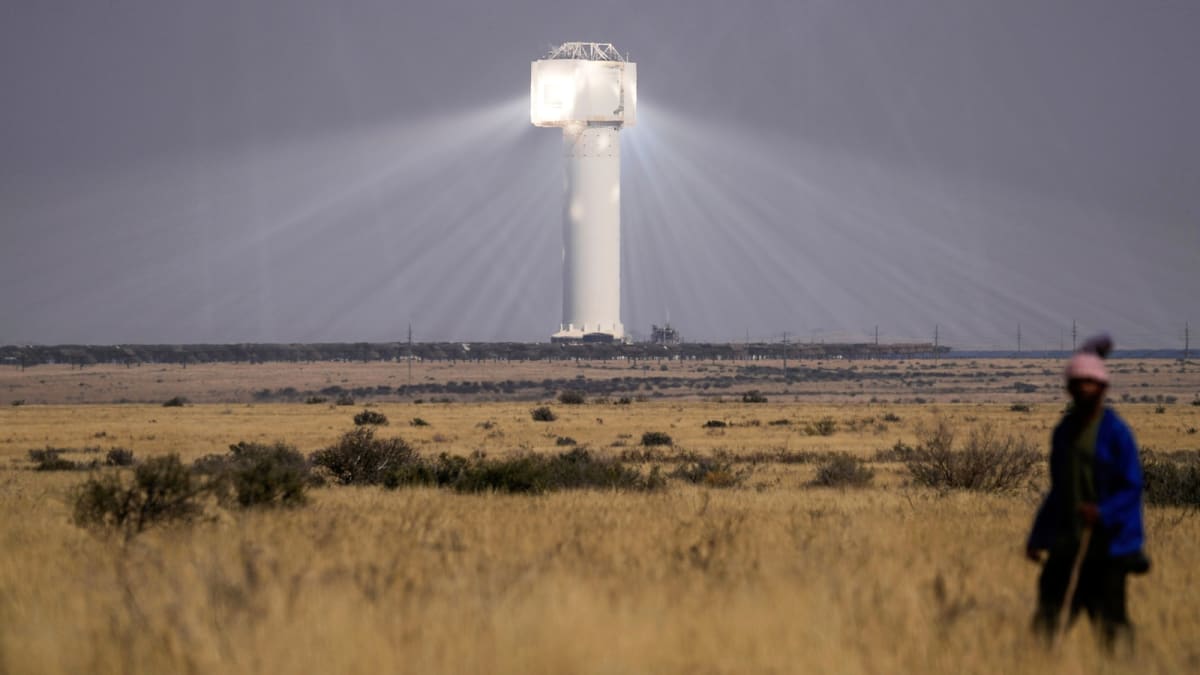 Solar panel arrays stretching across African landscape under bright blue sky